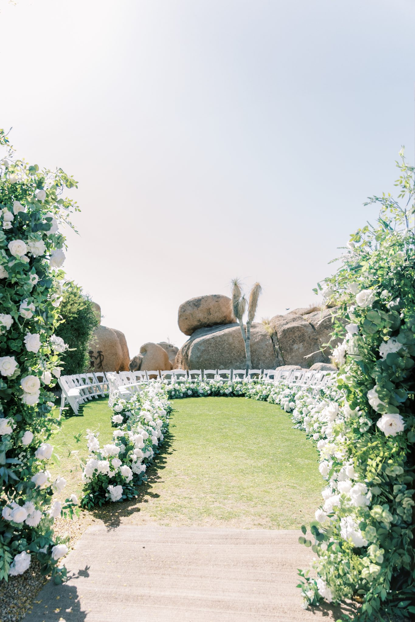 Outdoor ceremony space with circular seating and lush white florals against desert boulders at Boulders Resort & Spa Scottsdale by Hilton spring wedding in Scottsdale wedding rocky mountain bride.