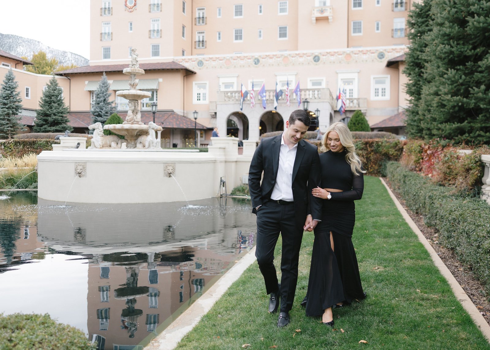 Couple walking hand in hand near the fountain during a Broadmoor fall engagement session rocky mountain bride.