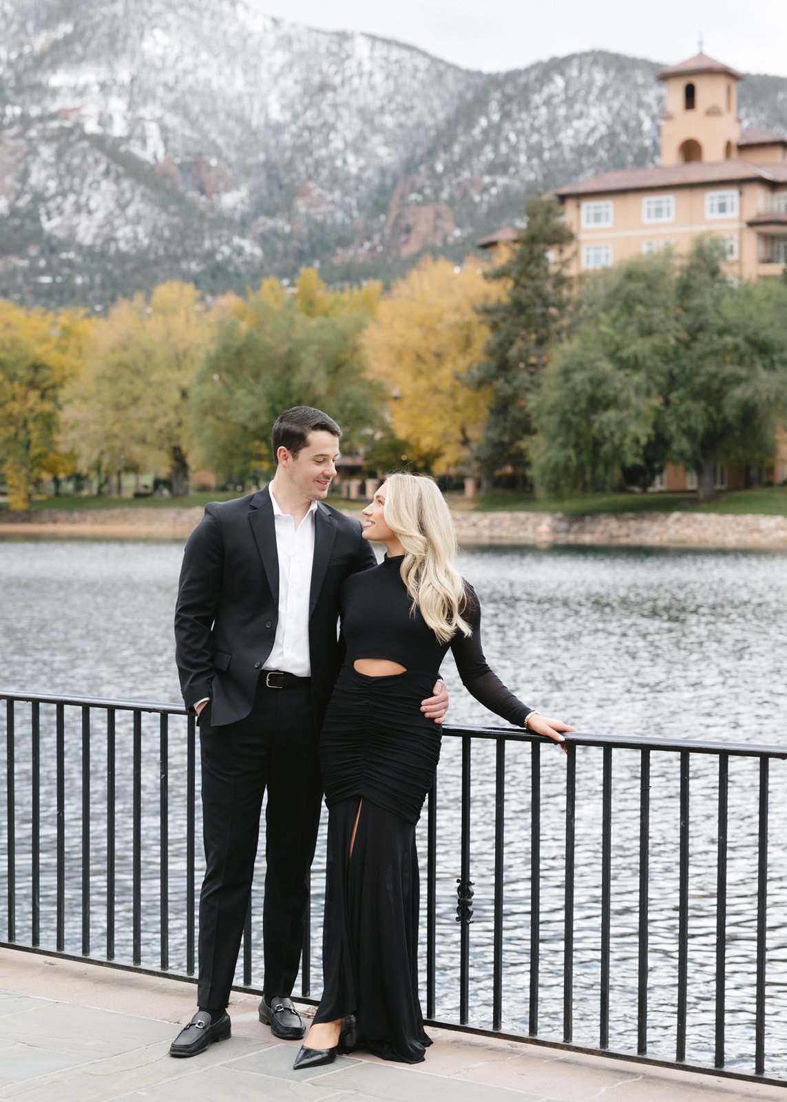 Romantic moment by the lake and mountain backdrop captured at a Broadmoor fall engagement session rocky mountain bride.