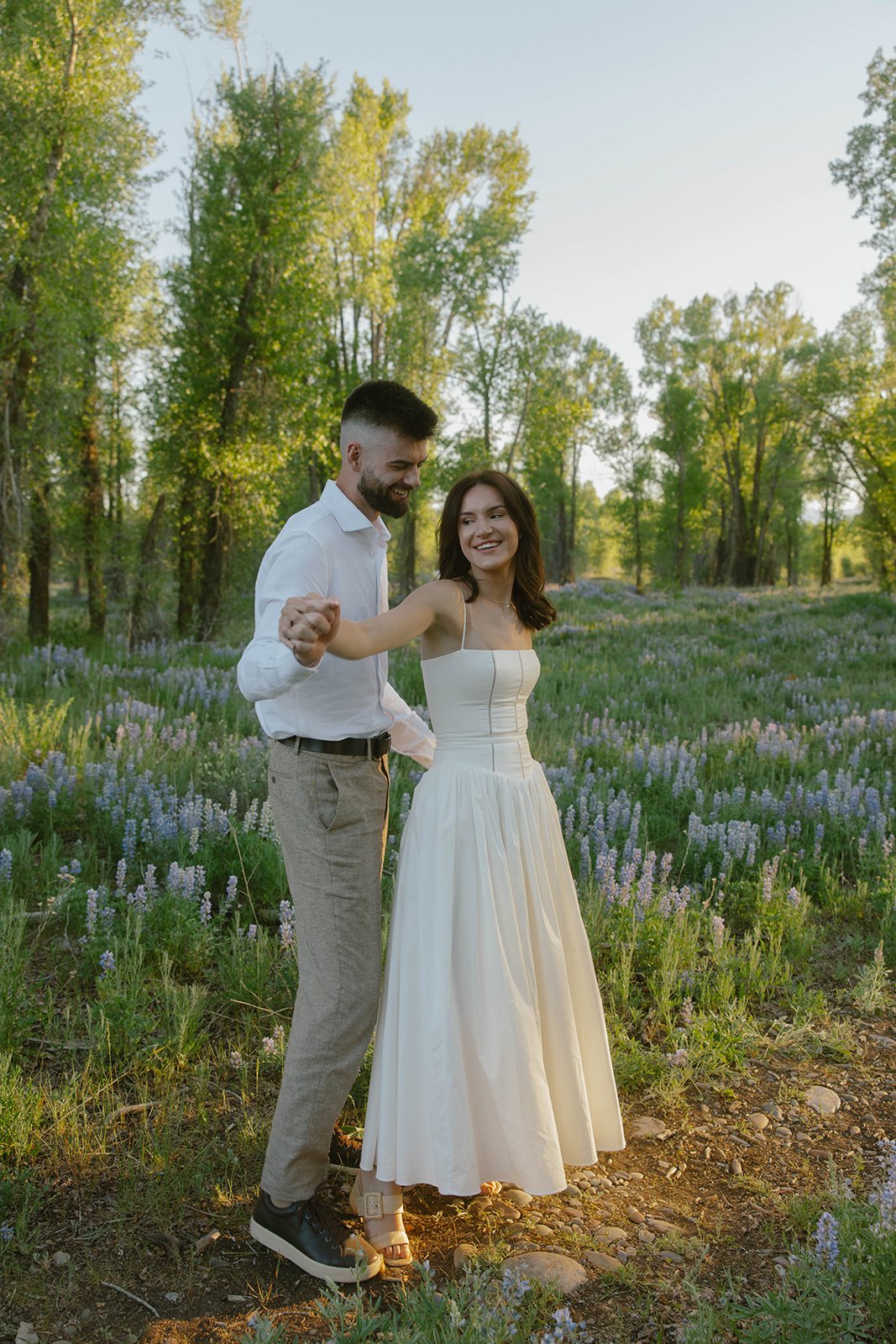 Couple dancing among blooming wildflowers during an Evable Photo wyoming engagement rocky mountain bride.