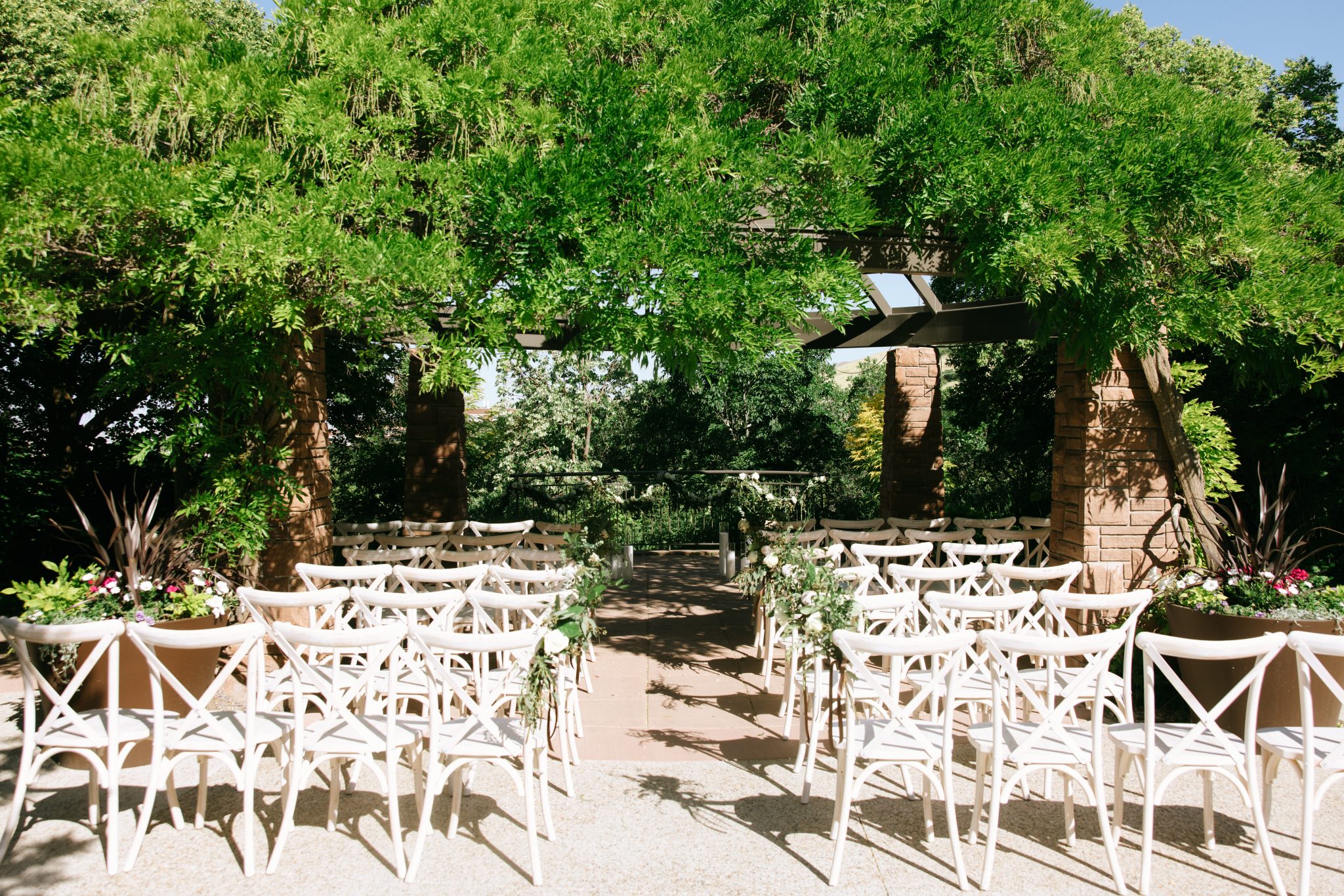 Outdoor ceremony space at a Red Butte Garden wedding with Luke Yamada rocky mountain bride, with white chairs, floral accents, and lush greenery overhead.