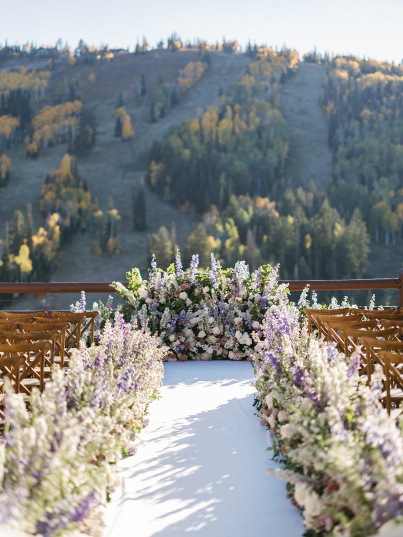 Mountain wedding ceremony aisle lined with purple and white florals overlooking fall foliage at Stein Eriksen Lodge in Deer Valley.